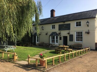 The Bull pub in Burrough Green with outdoor picnic tables on a grass lawn.