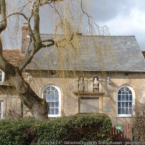 Burrough Green effigies Stone building with two arched windows and two carved figures above a blocked doorway.