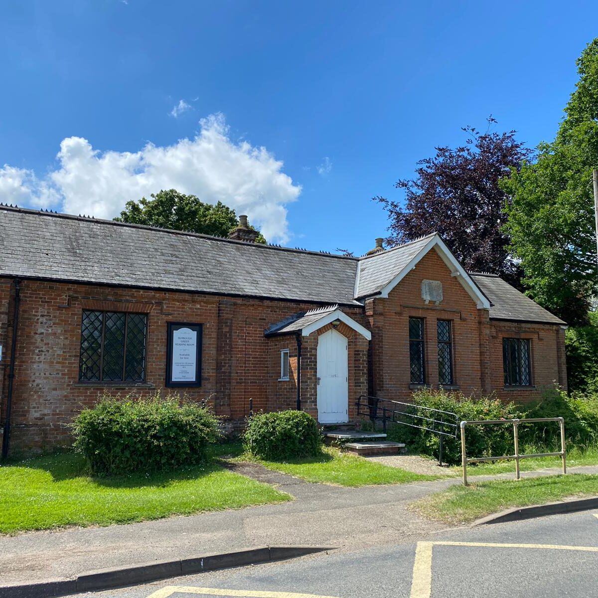 Exterior Reading Room A single-storey brick building with a gabled entrance, surrounded by trees and a green lawn.