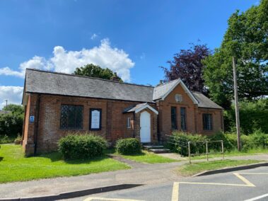 Exterior Reading Room A single-storey brick building with a gabled entrance, surrounded by trees and a green lawn.