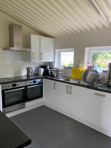 Modern kitchen with white cabinets, a double oven, and a sink on black worktops.